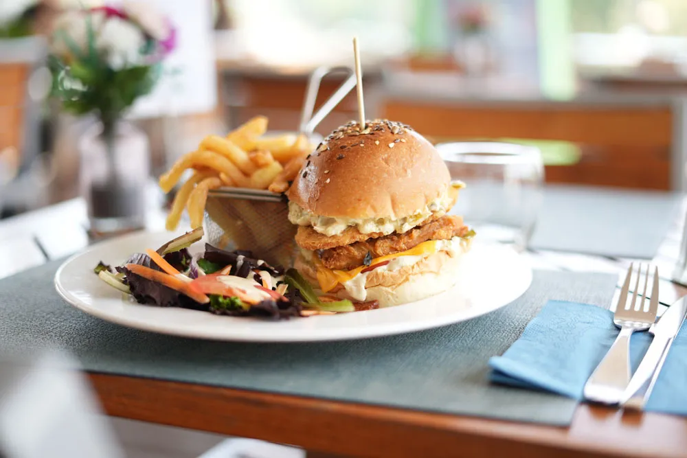 Burger au pain aux graines de sésame, servi avec un panier de frites fraîches