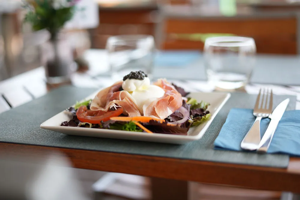 Salade au jambon cru et à la burrata, servie en terrasse